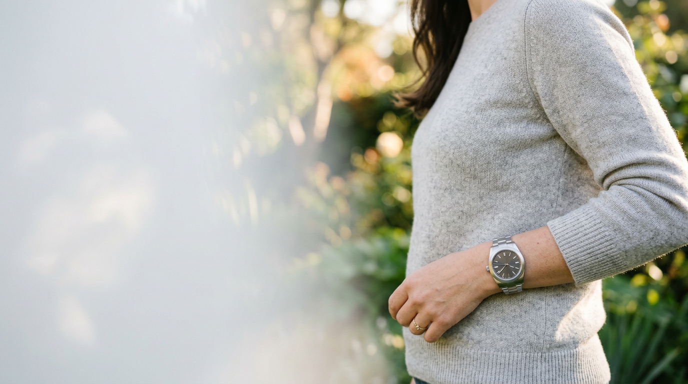 Une montre en acier au cadran sombre, portée au poignet dans la lumière douce d’un jardin